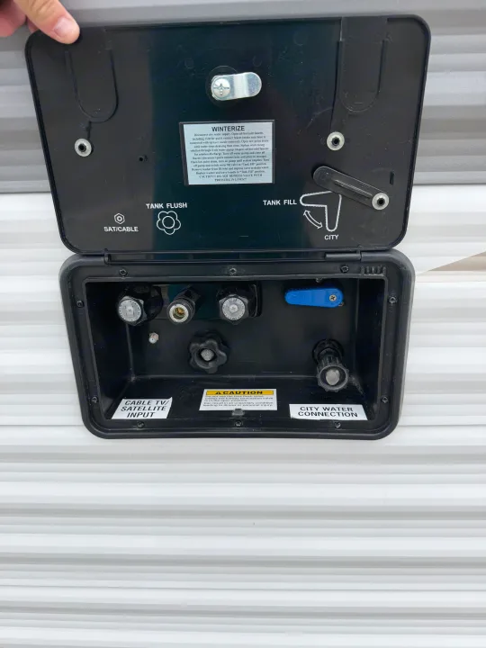 RV rental utility panel: connections for city water, tank fill/flush, winterization, and cable/satellite inputs.. Highland Ridge RV Open Range 2023