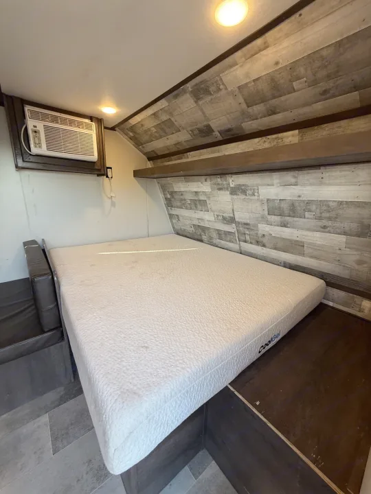 RV rental bedroom: Features a CoolGel mattress, wall AC, wood-paneled walls/ceiling, & recessed lights.. Coleman 17B Dutchmen 2022