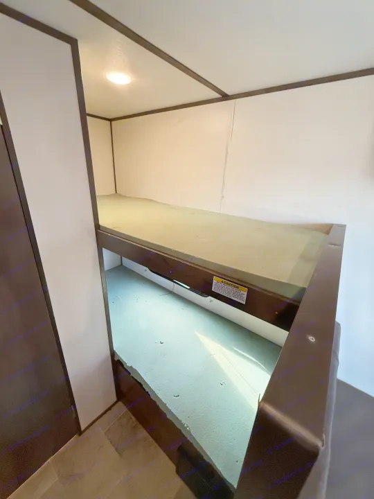 Inside an RV rental, showing the built-in bunk beds with foam mattresses and task lighting, ideal for compact sleeping.. Coleman 17B Dutchmen 2022