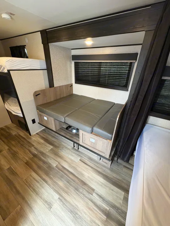 RV rental interior: cozy dinette converts to a bed, beside bunk beds & wood-look floor. Perfect for family campers.. Highland Ridge RV Open Range 2022