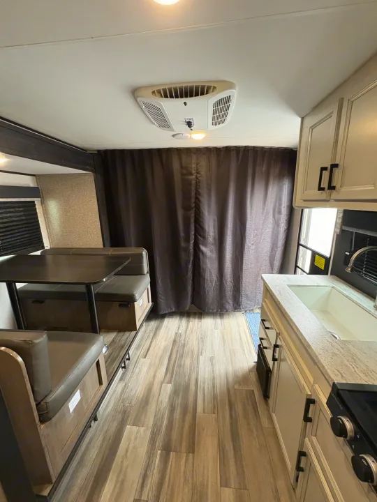 RV rental interior features a dinette, kitchenette with sink, and ceiling AC unit. Comfortable and compact living space.. Highland Ridge RV Open Range 2022