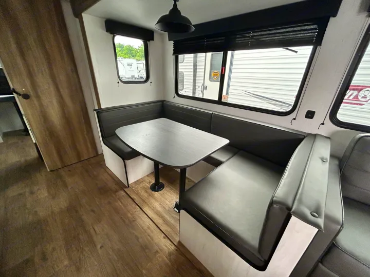 Cozy RV rental dinette with U-shaped seating, perfect for meals & relaxation. Features a gray table & dark benches.. Heartland RVs Trail Runner 2024