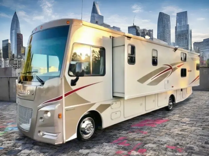 Explore the city in style! This spacious RV rental, with a slide-out, is parked on cobblestones by a modern skyline.. Winnebago Sunstar 2016