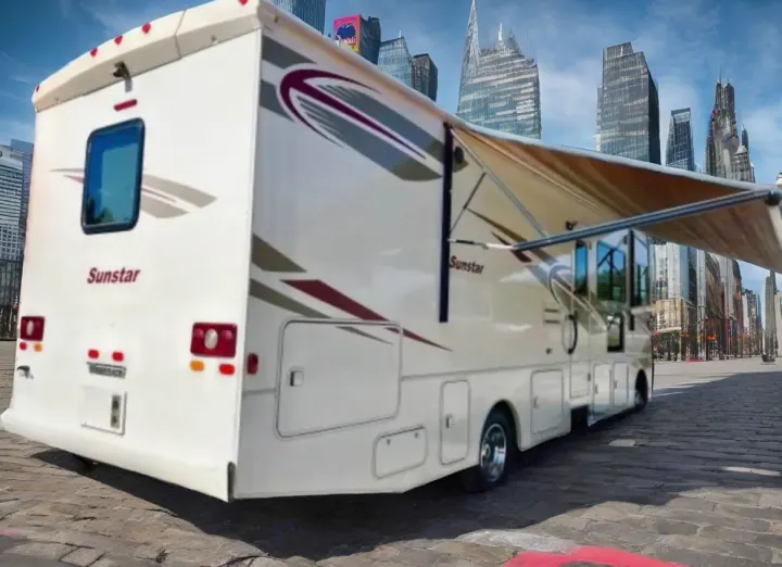 A white Sunstar rv rental with extended awning in a city street with tall buildings in the background, ready for travel.. Winnebago Sunstar 2016