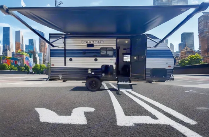 This Wolf Pup RV rental, a travel trailer with an open door & extended awning, sits in an urban lot with a cityscape view.. Forest River Cherokee Wolf Pup 2021