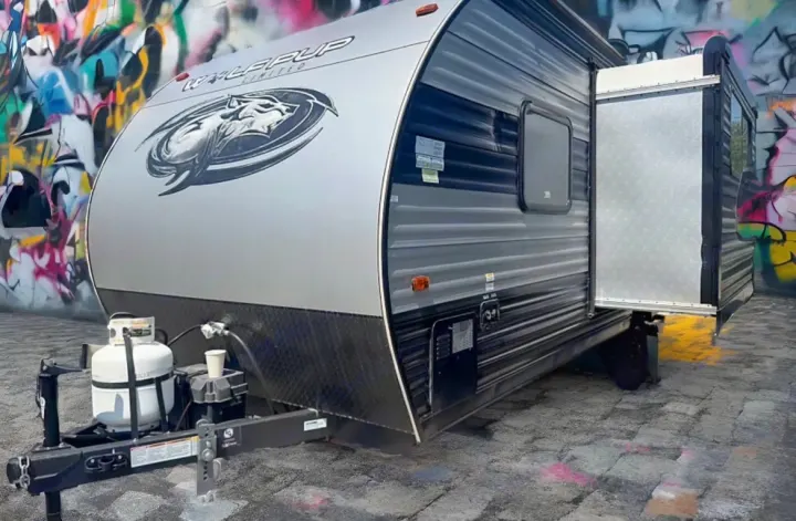 This gray and black travel trailer RV rental, a Wolf Pup model, features a slide-out, propane tank, and tow hitch.. Forest River Cherokee Wolf Pup 2021