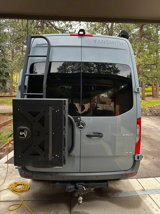 A gray Mercedes-Benz Sprinter RV rental's rear, featuring a ladder, cargo box, and tow hitch for adventures.. Mercedes-Benz Sprinter 2020