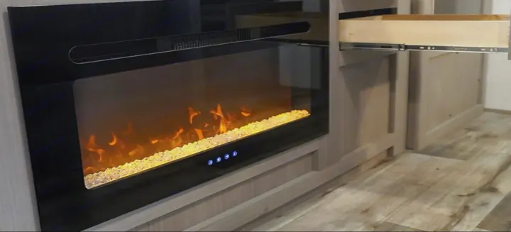 RV rental: Sleek electric fireplace with vibrant flames and glowing crystals, next to an open drawer in light cabinetry.. Dutchmen Coleman Lantern LT 2024