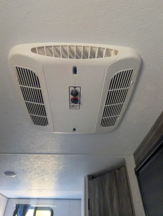 RV rental interior: A white Coleman's Mach air conditioner with fan/cool controls mounted on a textured ceiling.. Forest River Wildwood FSX Plantium 2022