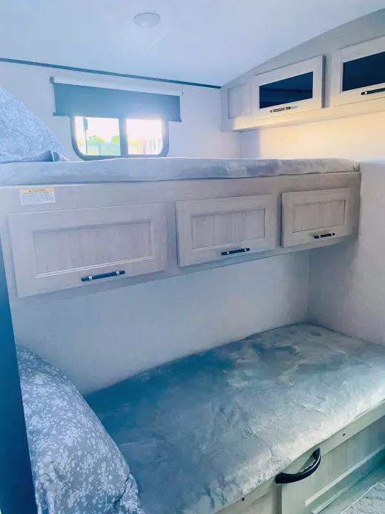 This RV rental offers comfortable bunk beds, built-in storage cabinets, and a bright window for natural light.. Crossroads RV Sunset Trail Super Lite 2025