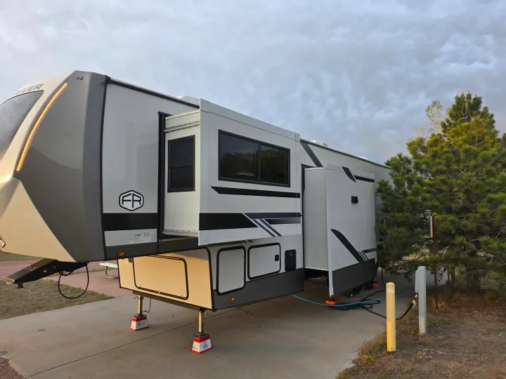 Modern fifth-wheel RV rental, fully set up with slides out at a campsite, ready for your next outdoor adventure.. Forest River Salem Hemisphere 2025