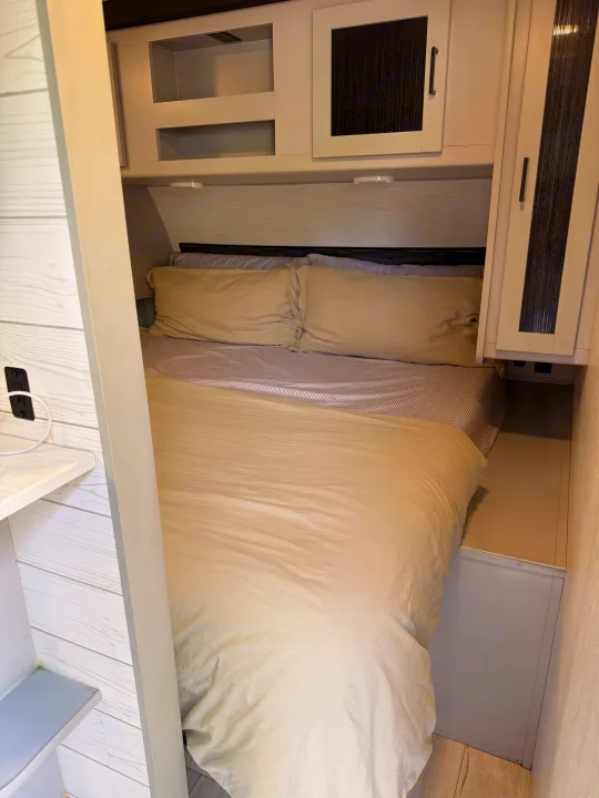 RV rental interior showing a compact, inviting bed with storage cabinets above and around it, ideal for travelers.. Heartland RVs North Trail 2022