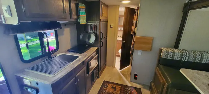 This rv rental interior features a compact kitchen with a sink, microwave, and fridge, a cozy dinette, and a bathroom.. Coachmen Apex Nano 2017