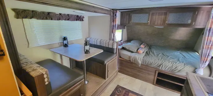 RV rental interior features a cozy dinette with decorative lanterns, a comfortable bunk bed, and overhead storage cabinets.. Coachmen Apex Nano 2017