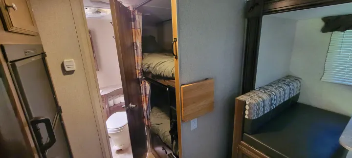 RV rental interior: bunk beds, bathroom, dinette, fridge, thermostat, and a wall-mounted folding table.. Coachmen Apex Nano 2017