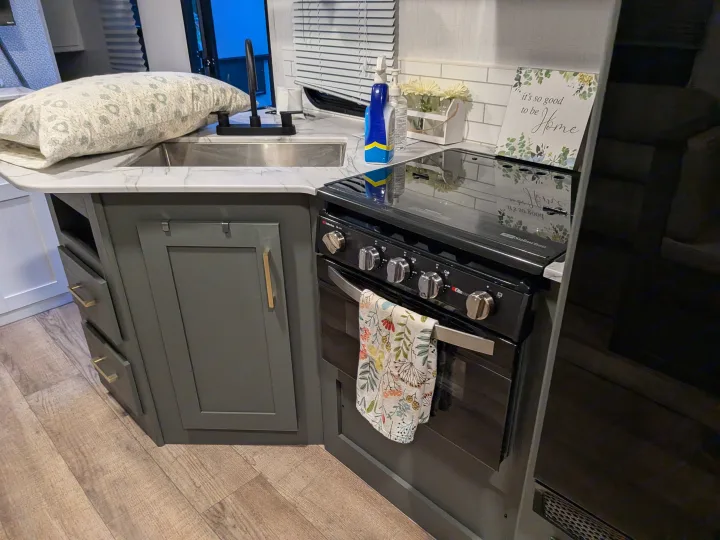 Modern RV rental kitchen with dark green cabinets, functional appliances, and homey decor for comfortable travels.. Eddie Bauer Eddie Bauer 2024