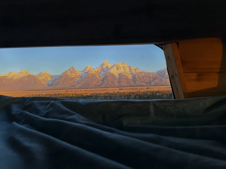 Stunning Grand Teton mountains at sunrise from an RV rental bed. Perfect nature view for your next adventure.. Ford Econolline 250s 2001