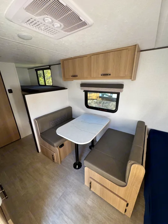 Inside a modern RV rental: dinette with table, bunk beds, overhead cabinets, and AC unit. Ready for your adventure!. Kodiak 178BHS 2026