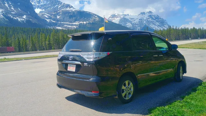 Black Toyota minivan parked on road, mountains & forest in background. A great alternative to an RV rental.. Toyota HIACE CAMPERVAN 2009