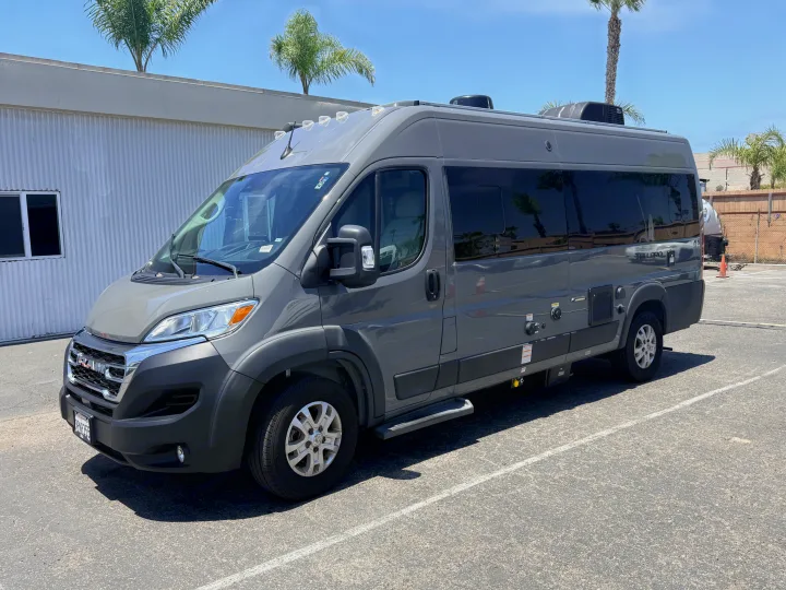 This grey Ram Tellaro Class B camper van, available for rv rental, is seen parked outdoors under a sunny sky.. Thor Tellaro 2024