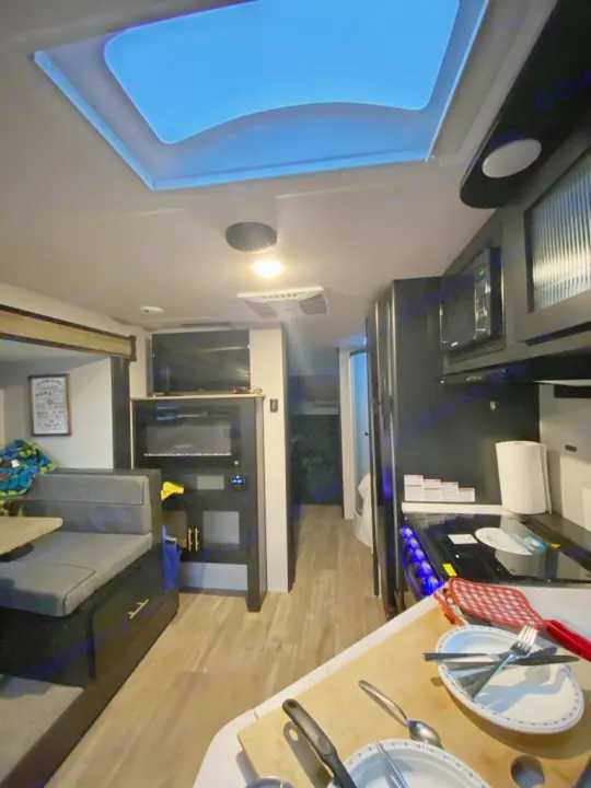 Explore this modern rv rental's interior, featuring a bright skylight, a functional kitchen with stove, and a cozy dinette seating area.. Forest River Cherokee Grey Wolf 2022