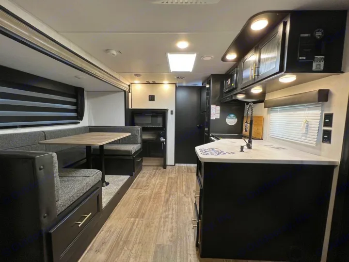 Inside a contemporary RV rental, featuring a comfortable dinette, practical kitchen area, and dark, modern interior.. Forest River Cherokee Grey Wolf 2022