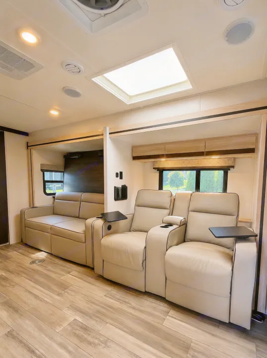 Spacious RV rental living area with comfortable beige recliners, a sofa, modern wood-look flooring, and an illuminating skylight.. Forest River Sunseeker MBS 2022