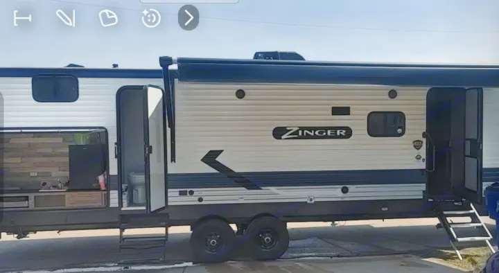 Explore this Zinger travel trailer RV rental. Its exterior showcases open doors to a kitchen/living area and a bathroom with entry steps.. Crossroads RV Zinger 2021