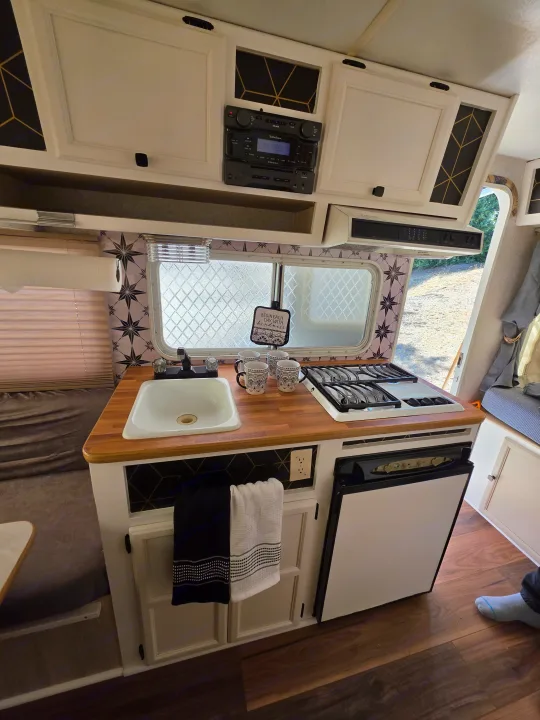 This rv rental offers a fully equipped kitchen: sink, stove, fridge, wood counter, and stylish geometric & star-patterned decor.. R-Vision Trail-Lite Bantam 2002