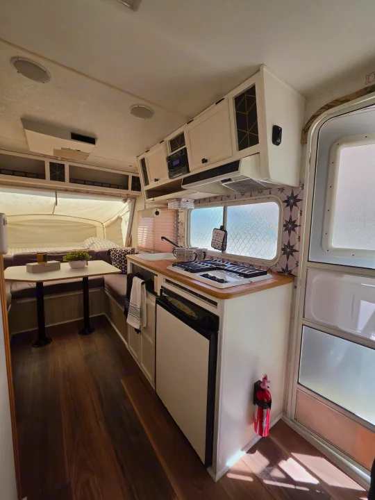Renovated RV rental interior: modern kitchen, cozy dinette, and bed area, with wood floors & patterned accents.. R-Vision Trail-Lite Bantam 2002