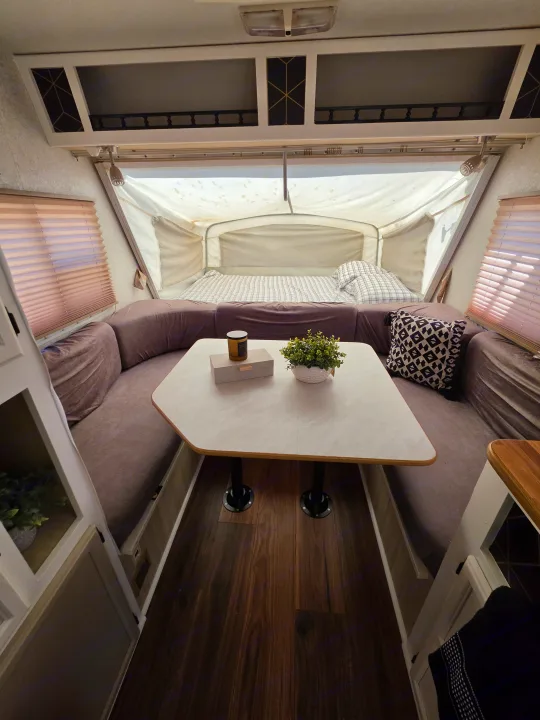 Inviting rv rental interior: dinette with L-shaped seating, center table, and a cozy pop-out bed at the rear. Home on wheels.. R-Vision Trail-Lite Bantam 2002