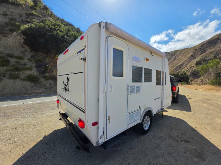 White travel trailer rv rental parked roadside with sunny mountains, perfect for your next adventure.. R-Vision Trail-Lite Bantam 2002