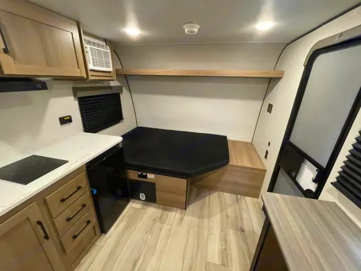 Cozy RV rental interior with a compact kitchen, dinette bench, and air conditioning, ready for your next adventure.. Keystone RV Coleman 2026