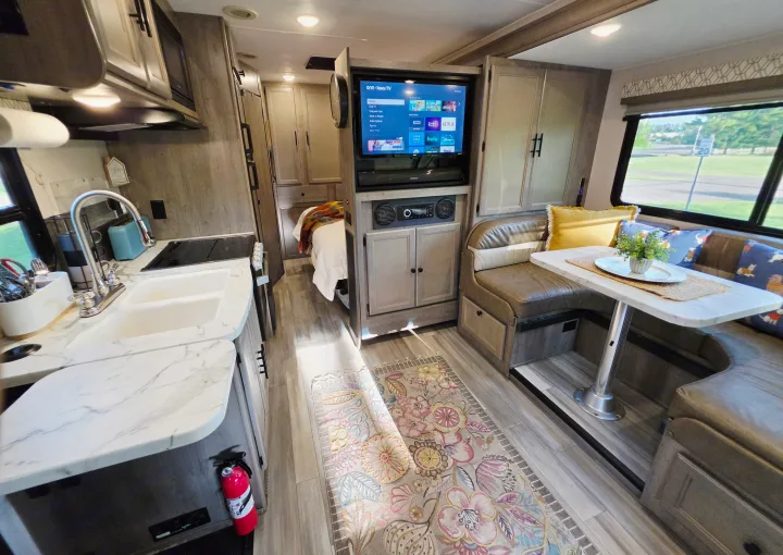 Cozy RV rental interior featuring a modern kitchen, comfortable dinette with a TV, and a glimpse of the bedroom.. Forest River Coachmen Prism 2018