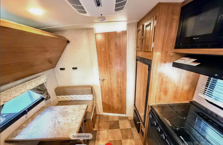 Cozy RV rental interior showing a dinette, kitchen with stove, microwave, fridge, bunk, and wood-paneled walls.. Forest River Flagstaff Micro Lite XLT 2017