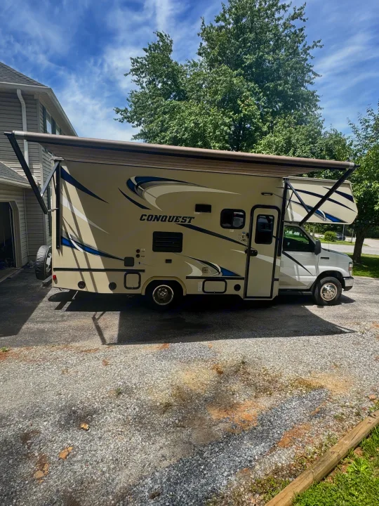 Spacious Class C RV rental, a tan Conquest motorhome with an extended awning, parked on a sunny day.. Gulf Stream Conquest 2019