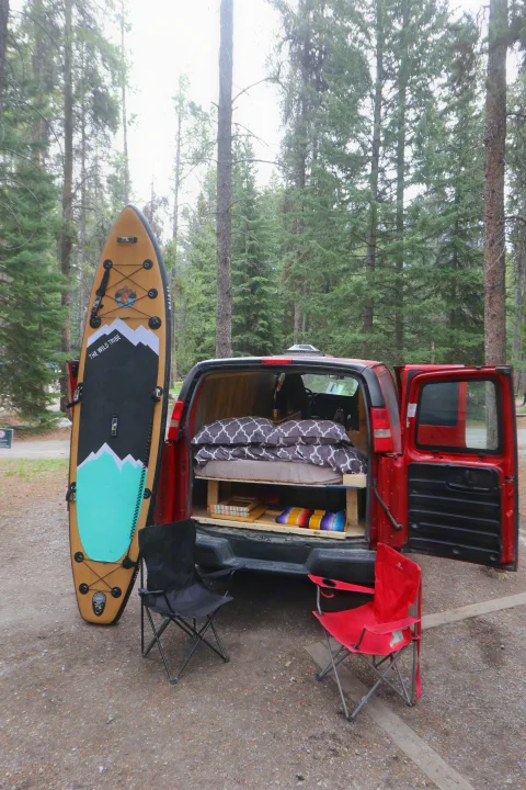 Adventure-ready RV rental van with a cozy bed, storage, and a paddleboard. Perfect for camping in the woods.. Glacier Campers Vanlife Explorer 2013