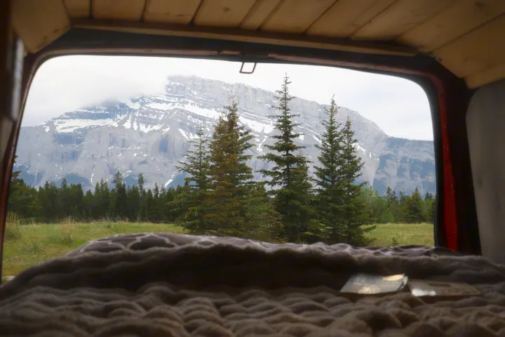 Relax in your RV rental with a breathtaking mountain and forest view from the cozy bed. Ideal for serene nature getaways.. Glacier Campers Vanlife Explorer 2013