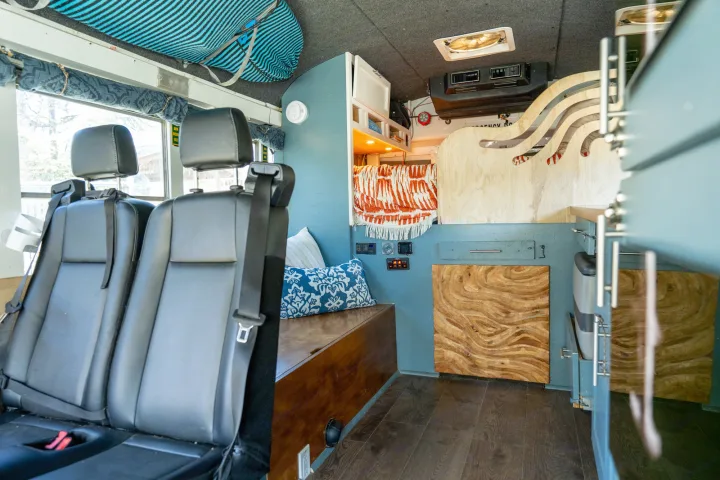 Inside a unique RV rental camper van, featuring custom wood details, black seats, and a comfy, functional living space.. Chevrolet Express s3500 2003