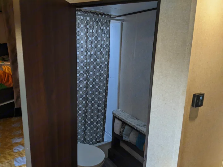 RV rental interior showing a compact bathroom with a patterned shower curtain, toilet, and towel storage.. Jayco Jay Flight 2020