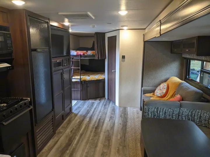 Cozy RV rental interior showing a kitchen, bunk beds, and living area with a comfortable couch.. Jayco Jay Flight 2020