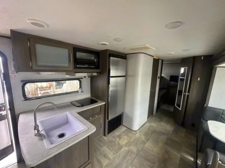 Modern rv rental interior with full kitchen, dining area, and hallway to living space.. Dutchmen Kodiak SE 2021