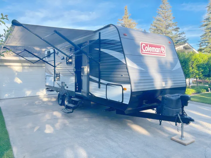 Coleman travel trailer with extended awning, parked in a sunny driveway. Ideal for an RV rental trip.. Dutchmen Coleman Lantern 2018