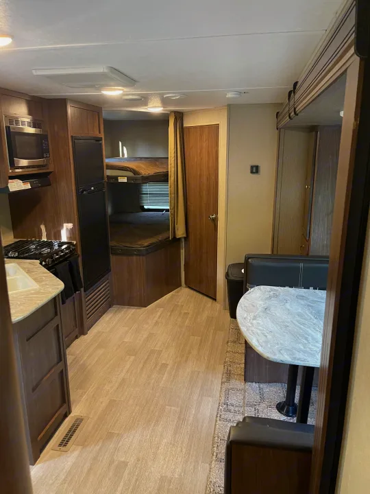 Bright RV rental interior with a fully-equipped kitchen, cozy bunk beds, and a dinette, offering comfort for travelers.. Dutchmen Coleman Lantern 2018