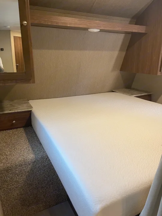 Cozy RV rental bedroom featuring a queen memory foam mattress, overhead storage, and built-in nightstands.. Dutchmen Coleman Lantern 2018