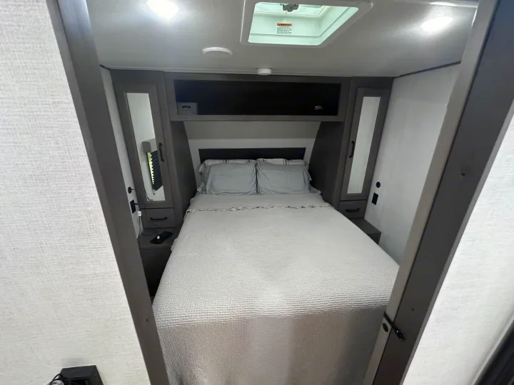 Cozy RV rental bedroom with a comfy bed, overhead storage, and functional bedside cabinets, perfect for travel.. Grand Design Transcend Xplor 2024