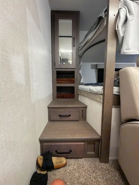 Inside this rv rental, find bunk beds, convenient storage steps with a mirrored cabinet, shelves, and drawers, optimizing space.. Grand Design Transcend Xplor 2024