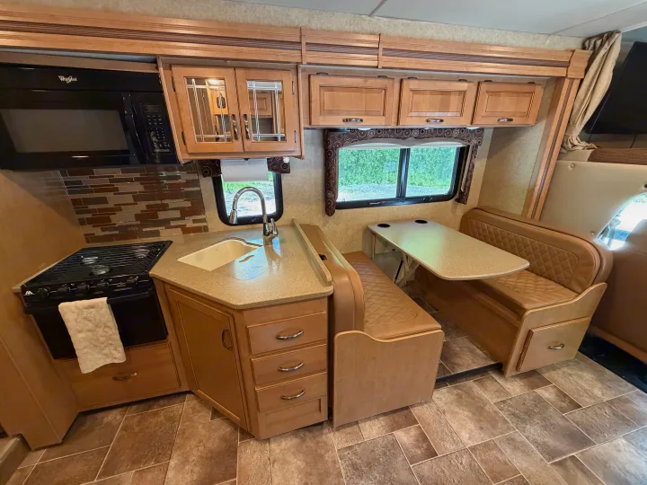 This RV rental offers a well-appointed kitchen with microwave, stove, sink, cabinetry, and a comfortable dinette with window views.. Thor Four Winds 2016