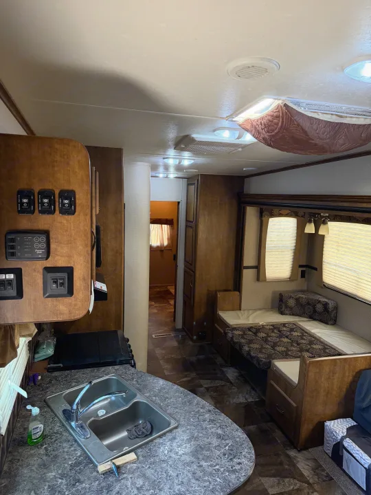 Explore this RV rental's interior: a kitchen with sink and control panel, plus a comfortable dinette seating area with patterned cushions.. Crossroads RV Rezerve 2015