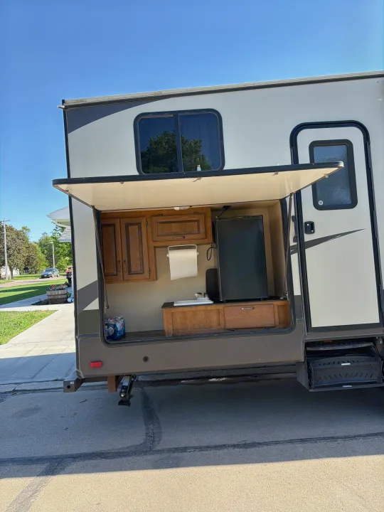 This RV rental features a convenient outdoor kitchen with cabinets, a sink, and a mini-fridge, perfect for camping.. Crossroads RV Rezerve 2015